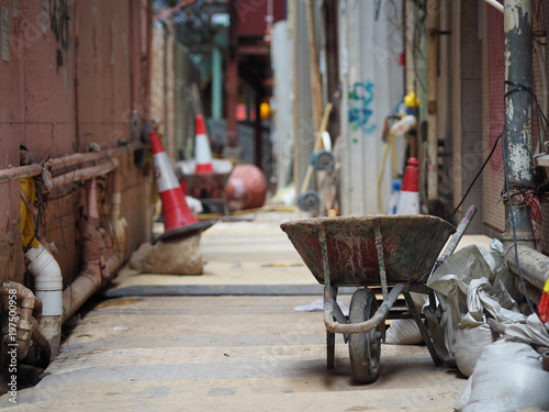 A wheelbarrow with some cement bags is in an alley. photo