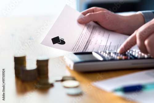 Man counting college savings fund, tuition fee or student loan with calculator. Education price and expenses concept. Money and papers on table. Calculating budget and planning finance. photo