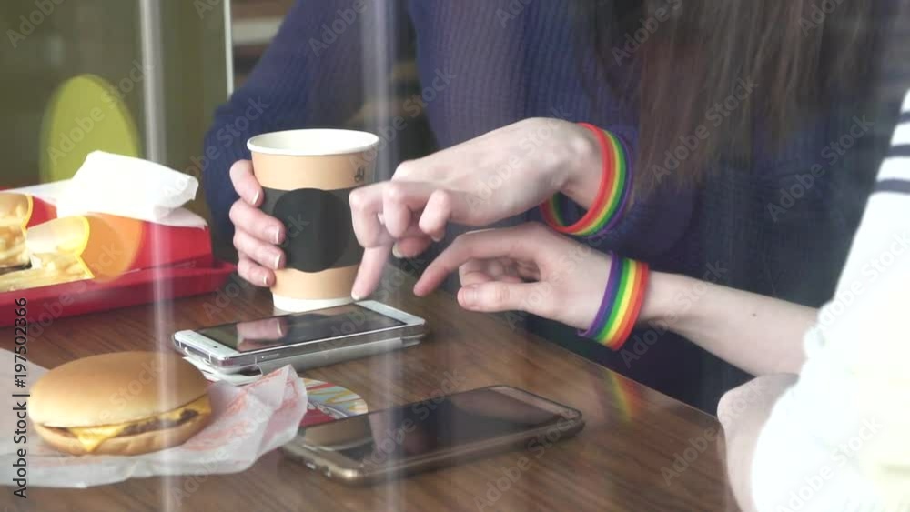 women's hands in the cafe using a phone with LGBT bracelets close up women's hands in the cafe using a phone with LGBT bracelets close up