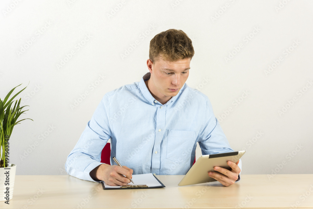 Portrait of a handsome young man using digital tablet by the desk Portrait of a handsome young man using digital tablet by the desk
