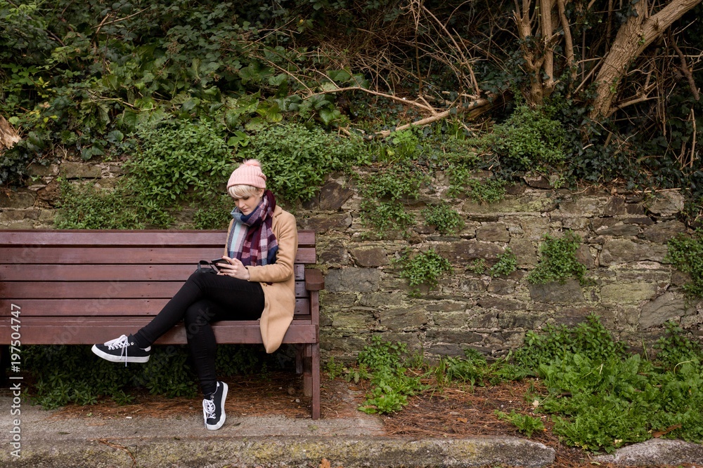 Woman sitting on bench and using mobile phone Woman sitting on bench and using mobile phone