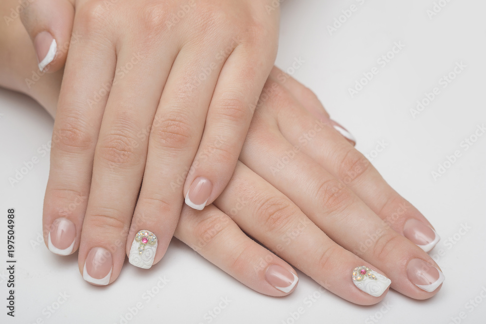 Manicure with rhinestones in the shape of hearts and pink balls on white and red nail Polish on a white background. Manicure with rhinestones in the shape of hearts and pink balls on white and red nail Polish on a white background.
