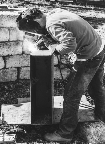 a welder puts the seam on the metal electro arc welding, black and white photo photo