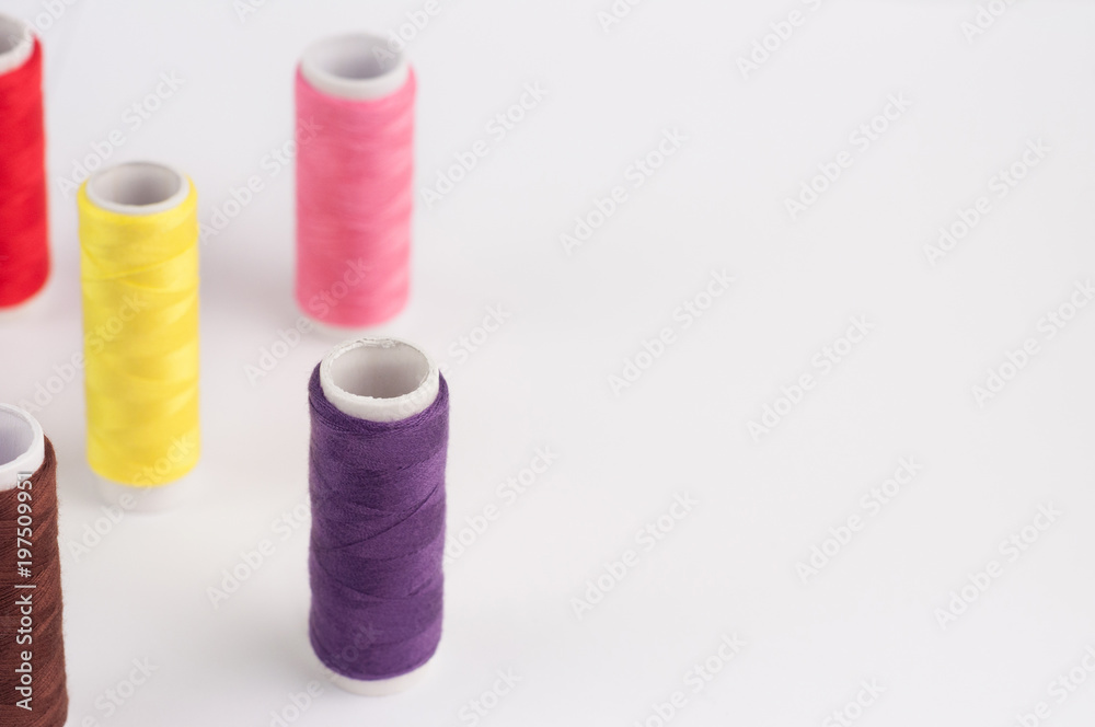 Lot of bobbins of new colorful threads on white background Lot of bobbins of new colorful threads on white background