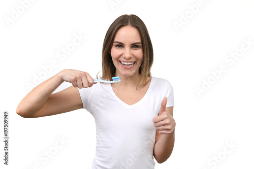 Hübsche blonde Frau lacht, hält eine Zahnbürste in der Hand und Daumen hoch