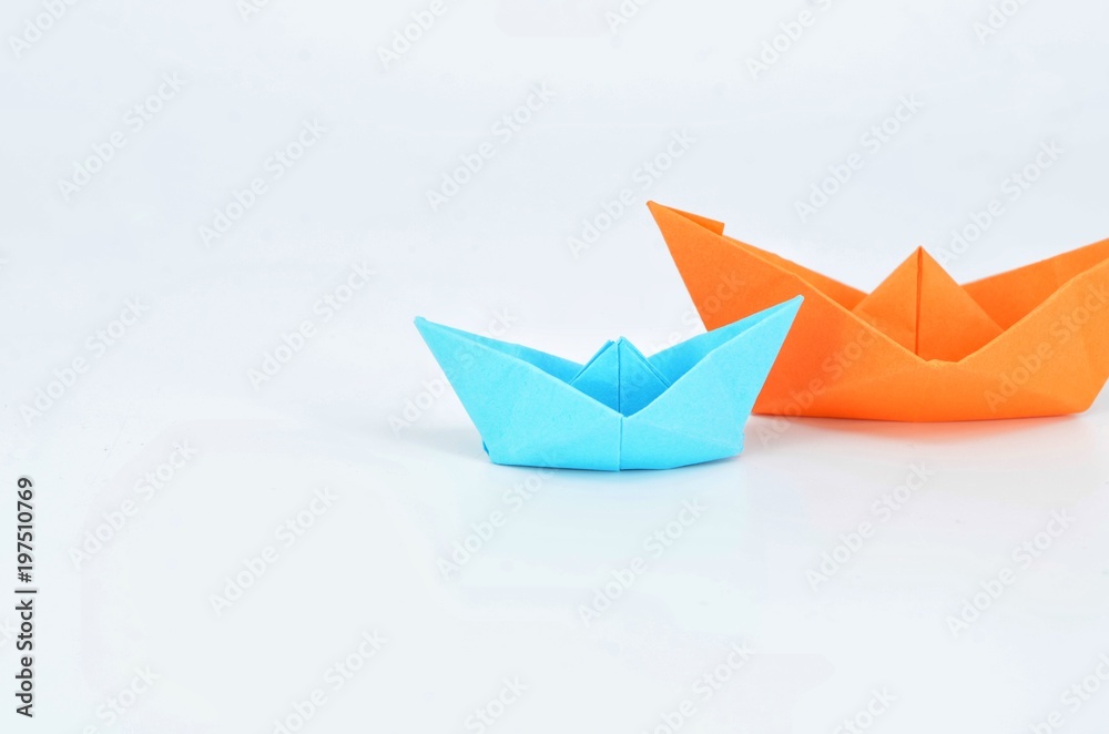 Obraz premium Origami boats orange and blue o white background.