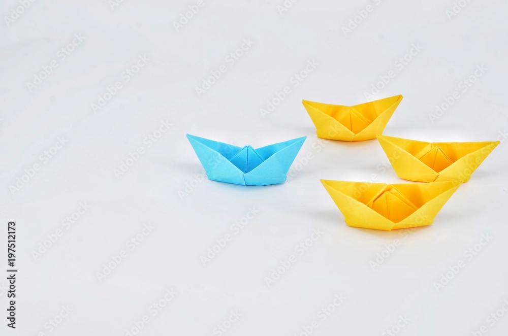 Leadership concept with a blue paper ship leading among yellow ships. Leadership concept with a blue paper ship leading among yellow ships.