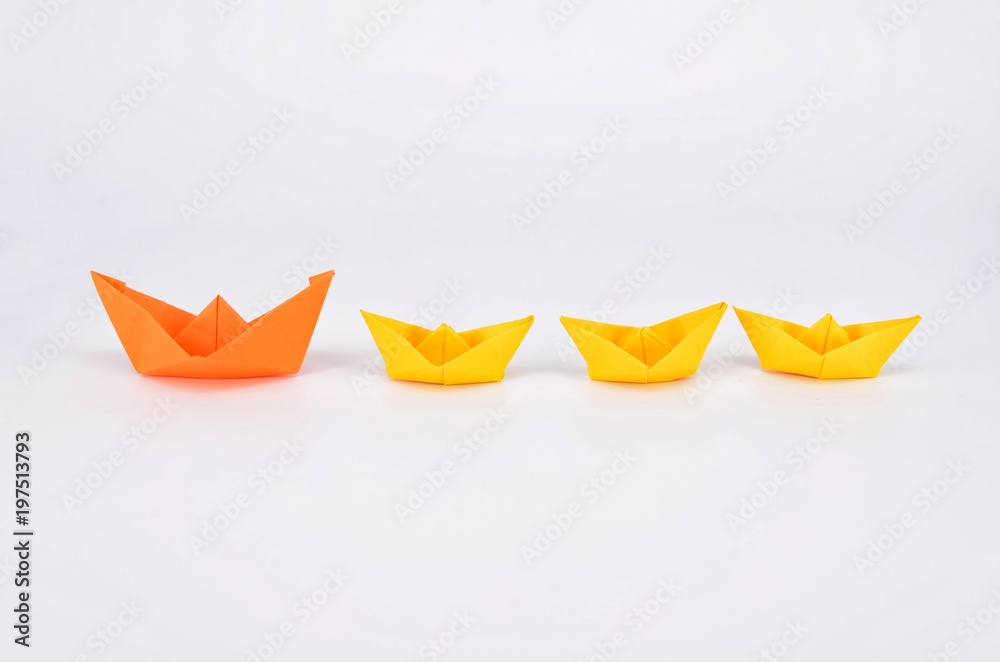 Leadership concept with a orange paper ship leading among yellow ships. Leadership concept with a orange paper ship leading among yellow ships.