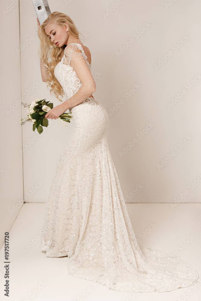 Bride in beautiful dress standing indoors in white studio interior like at home. Trendy wedding style shot. Young attractive caucasian model like a bride tender looking. Bride in beautiful dress standing indoors in white studio interior like at home. Trendy wedding style shot. Young attractive caucasian model like a bride tender looking.