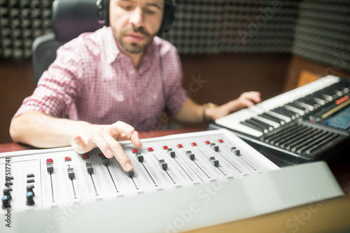 Musician mixing and composing music in soundproof studio