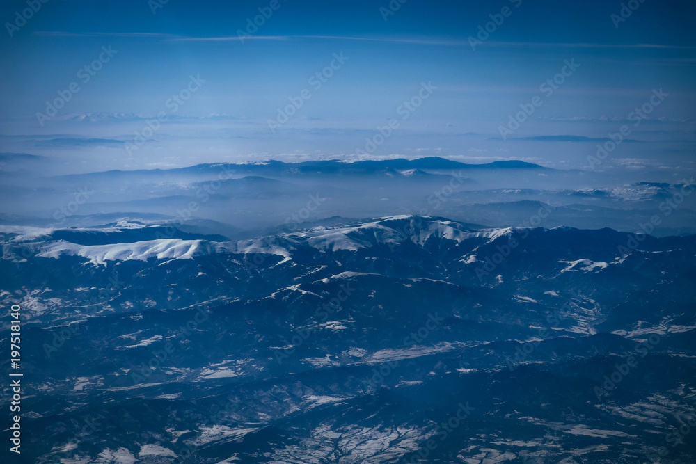 Airplane view on the beautiful alpine mountains top, covered with ice.