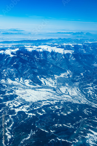 Airplane view on the beautiful alpine mountains top, covered with ice.