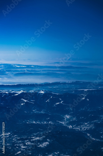 Airplane view on the beautiful alpine mountains top, covered with ice.