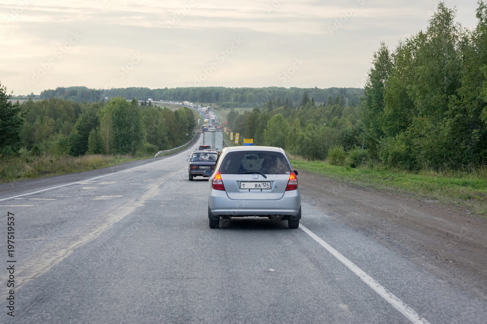 Cars drive along the highway past a green forest in the evening. Cars drive along the highway past a green forest in the evening.