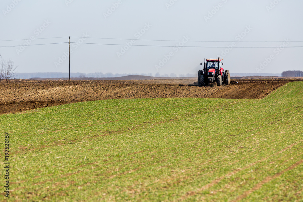 Obraz premium Tractor cultivating field at spring