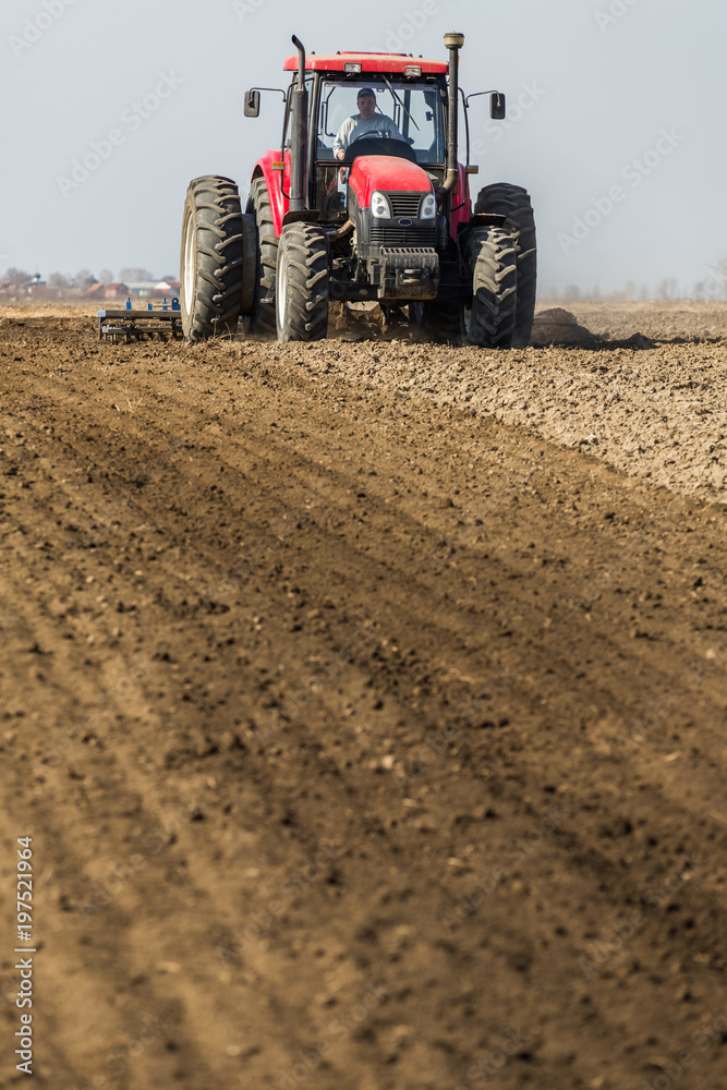 Tractor cultivating field at spring