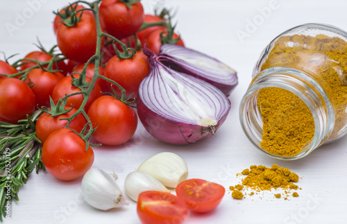 Bunch of tomatoes with garlic, rosemary and curry on white background