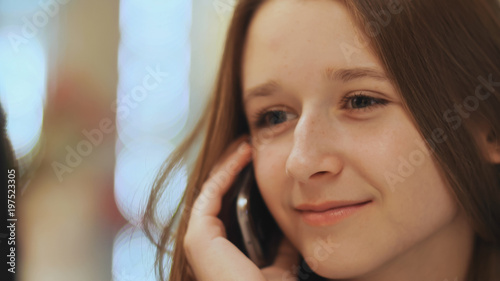 Cute young girl talking on a cell phone. Close-up.