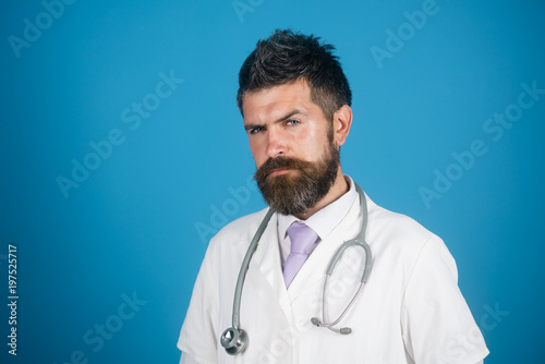 Physician with beard in white medical robe. Medical and healthcare concept - doctor with stethoscope in hospital. Medicine and health - serious handsome male doctor in white medical gown. Copy space.