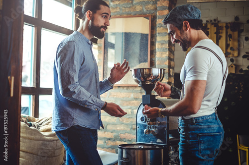 Male owners looking at coffee bean by the coffee roaster