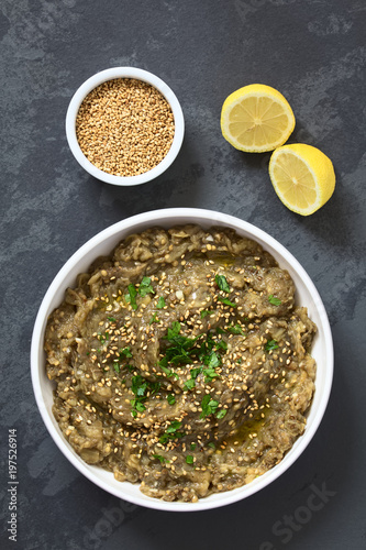 Frischer Auberginen-Dip oder Aufstrich, Baba Ghanoush in der Arabischen Küche, mit Sesam, Petersilie und Olivenöl in Schüssel serviert, fotografiert auf Scieferplatte mit natürlichem Licht