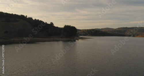 Flying over magical mystic lake sunrise near a misty forest pivot aerial reveal shot photo