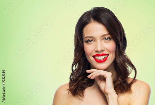 beauty, make up and people concept - happy smiling young woman with red lipstick posing over green background