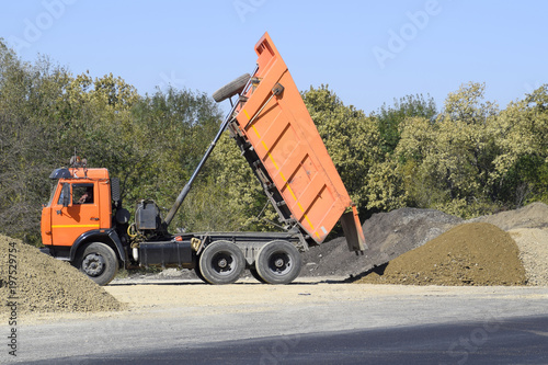 The dump truck unloads rubble. The truck dumped the cargo. Sand and gravel. Construction of roads photo