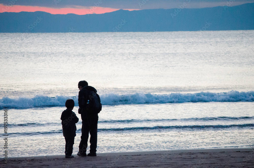 Son and Father are looking at something around their feet is taken in Kanagawa, Japan. It was in the winter season.