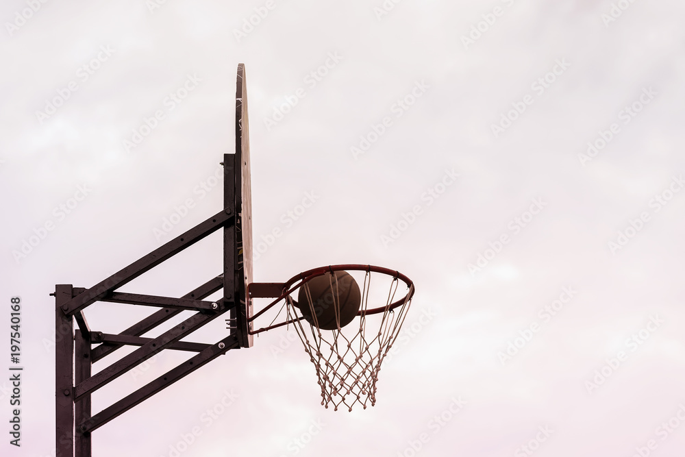 Basketball shield, ball going through basket on background of sky. Concept of sport, hit accuracy, active lifestyle. Copy space