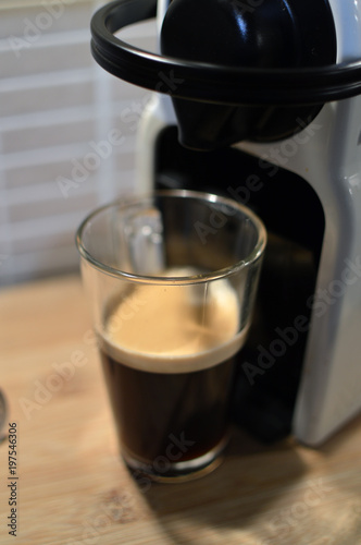 Closeup of home coffee machine brewing coffee on wooden table