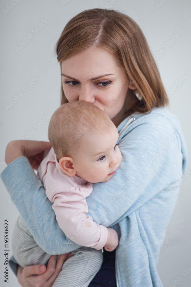 a young mother holds a baby in her arms and kisses her daughter in the head. Mom is going through a young mother holds a baby in her arms and kisses her daughter in the head. Mom is going through