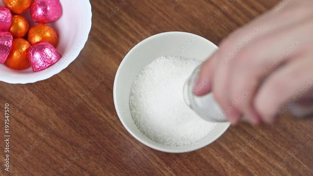 Man hands putting chocolate candy, and pouring sugar into teacup Man hands putting chocolate candy, and pouring sugar into teacup