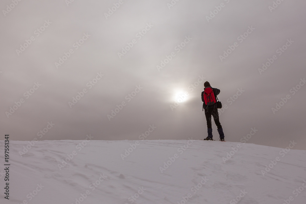 Man taking photo of pale sun on a snowy slope in a gray day, Col Visentin, Belluno, Italy Man taking photo of pale sun on a snowy slope in a gray day, Col Visentin, Belluno, Italy