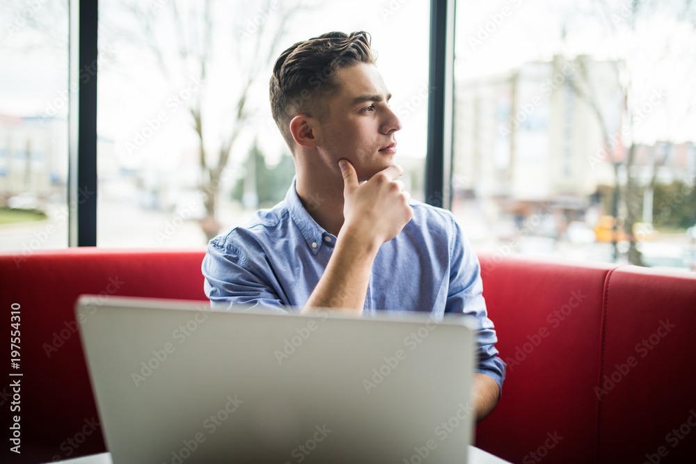 Handsome young male entrepreneur on laptop while sitting in cafe Handsome young male entrepreneur on laptop while sitting in cafe