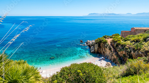 The paradise beach: clear turquoise sea water, white pebbles beach and a house on the beach, at the natural reserve of “Riserva dello Zingaro, San Vito lo Capo, Sicily, Italy.