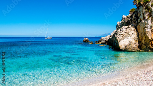 A sailing boat into the turquoise Mediterranean Sea, at San Vito Lo Capo, Sicily, Italy.