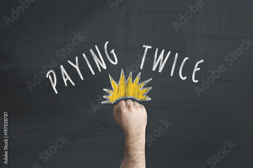 Fist cracking punching Paying twice text written on chalkboard