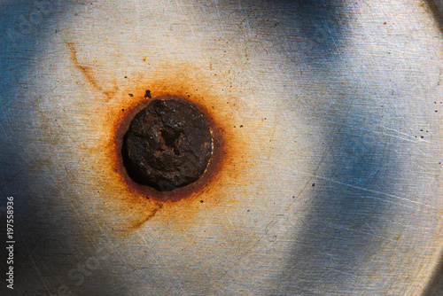 Old burnt, rusty bolt in a metal surface