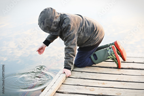 A child playing with water off a dock