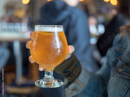 Fotografie Woman holding light beer snifter in bar/brewery