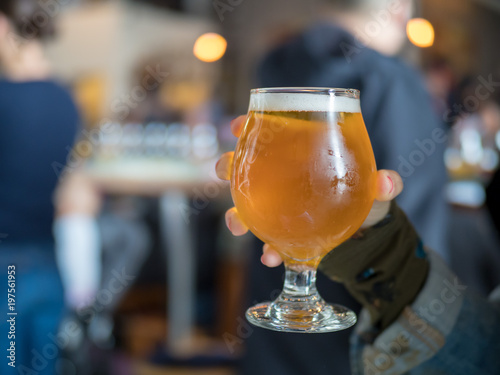 Hand holding a light beer snifter in bar/brewery
