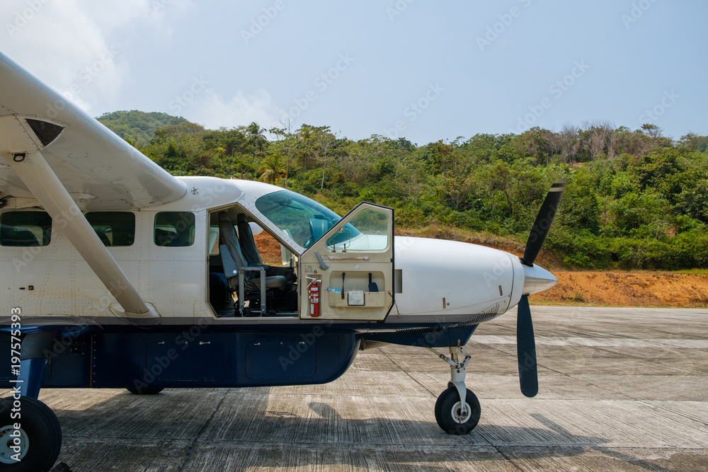 Small propeller airplane with open cockpit door on runway Small propeller airplane with open cockpit door on runway