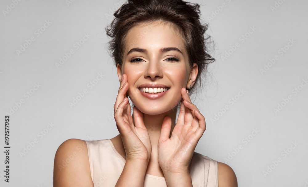 Fototapeta premium Portret uśmiechnięta młoda piękna kobieta z białymi zębami, świeżą skórą i naturalnym makijażem na szarym tle