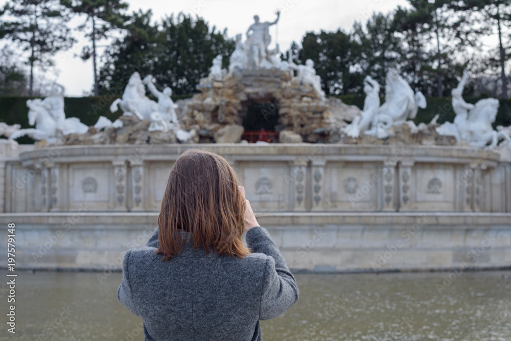girl takes a photograph of a monument in the city