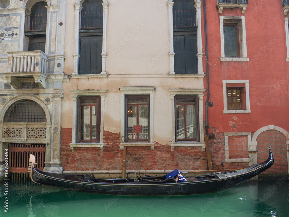 traditional gondola moored at the entrance of a palace in a canal in Venice, Italy.