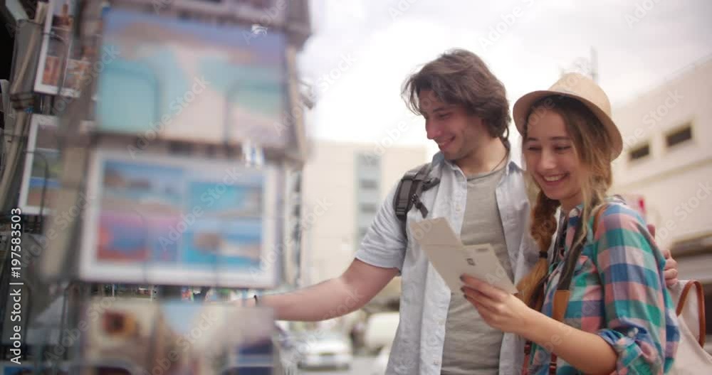Young tourists couple choosing postcards at souvenir shop