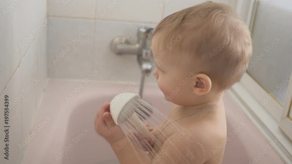 Baby boy a shower with play water in bathroom. Baby with Cross Pendant Baby boy a shower with play water in bathroom. Baby with Cross Pendant