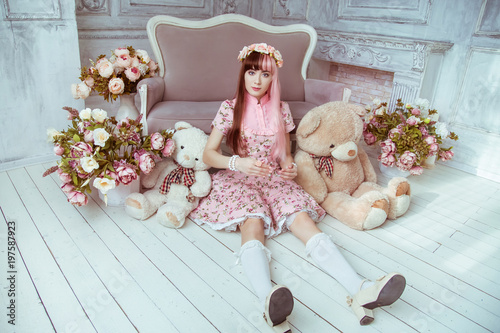 Tableau sur toile Beautiful young woman doll in a pink dress in a room with flowers, sits on the floor with other toys and plush bear, lolita