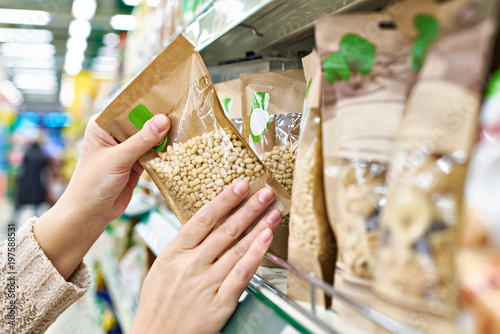 Foto Hands with packaging of pine nuts in store